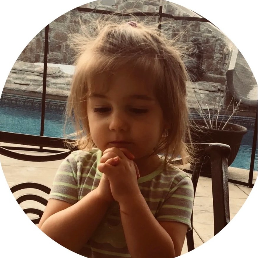 A young girl with hands folded in prayer